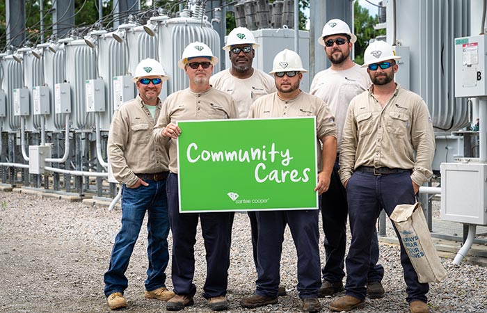 Utility workers with 'Community Cares' sign