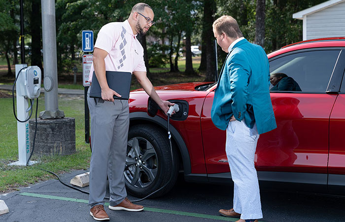 Two men charging electric vehicle